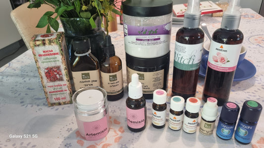 Collection of various bottles and containers on a table with a plant and box in the background. Talya Acne