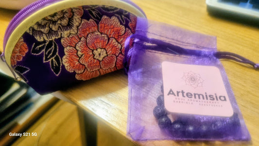 Decorative pouch with floral design and Artemisia branded bag on a wooden surface