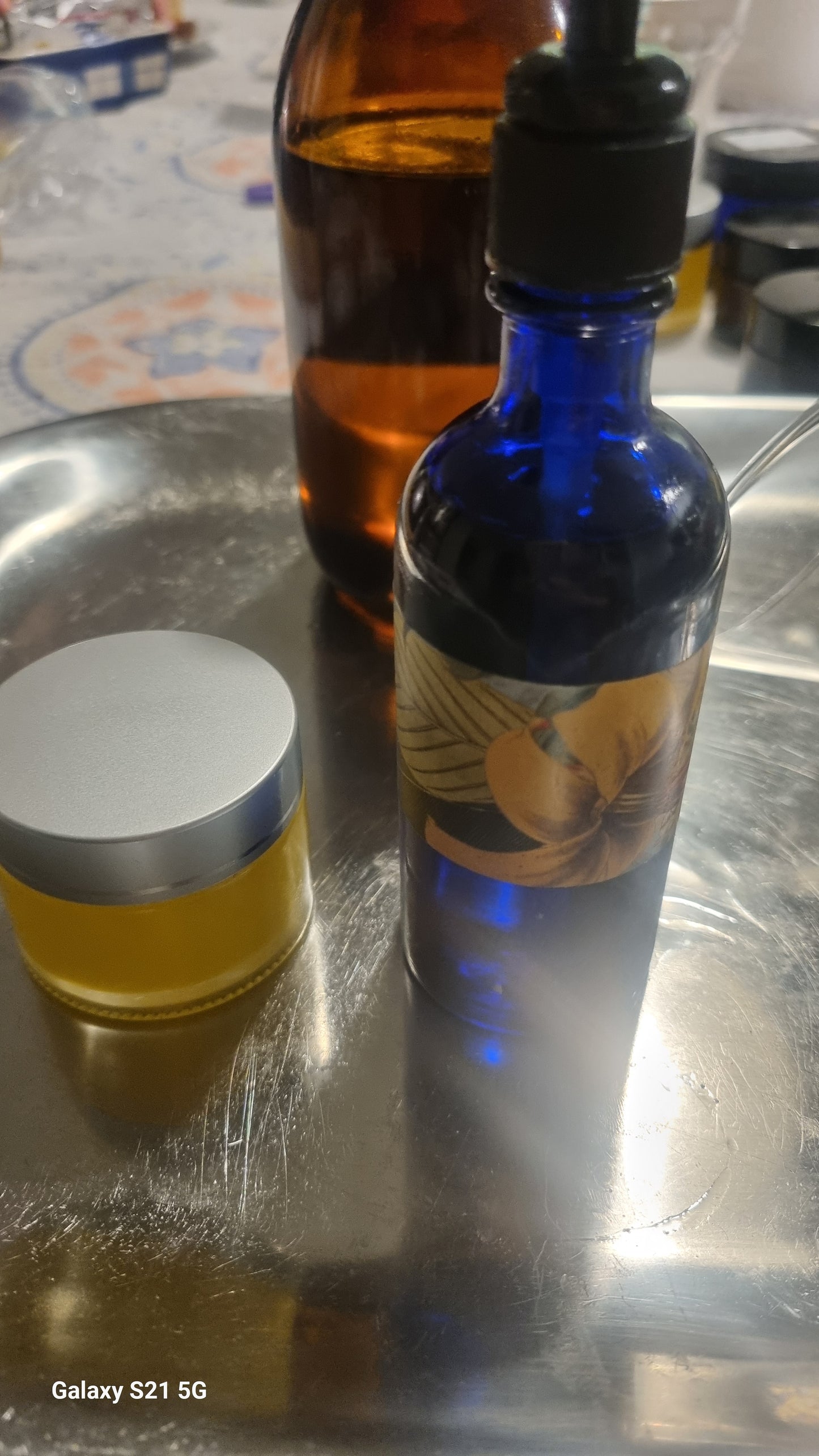 A photo showing two bottles of aromatic oils, one with a darker hue and another with a lighter, yellowish color, likely representing the Body Orange and Geranium Sesame Oil product.