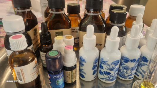 Collection of various blue and White Ceramic bottles including droppers and carrier oil containers on a reflective surface.