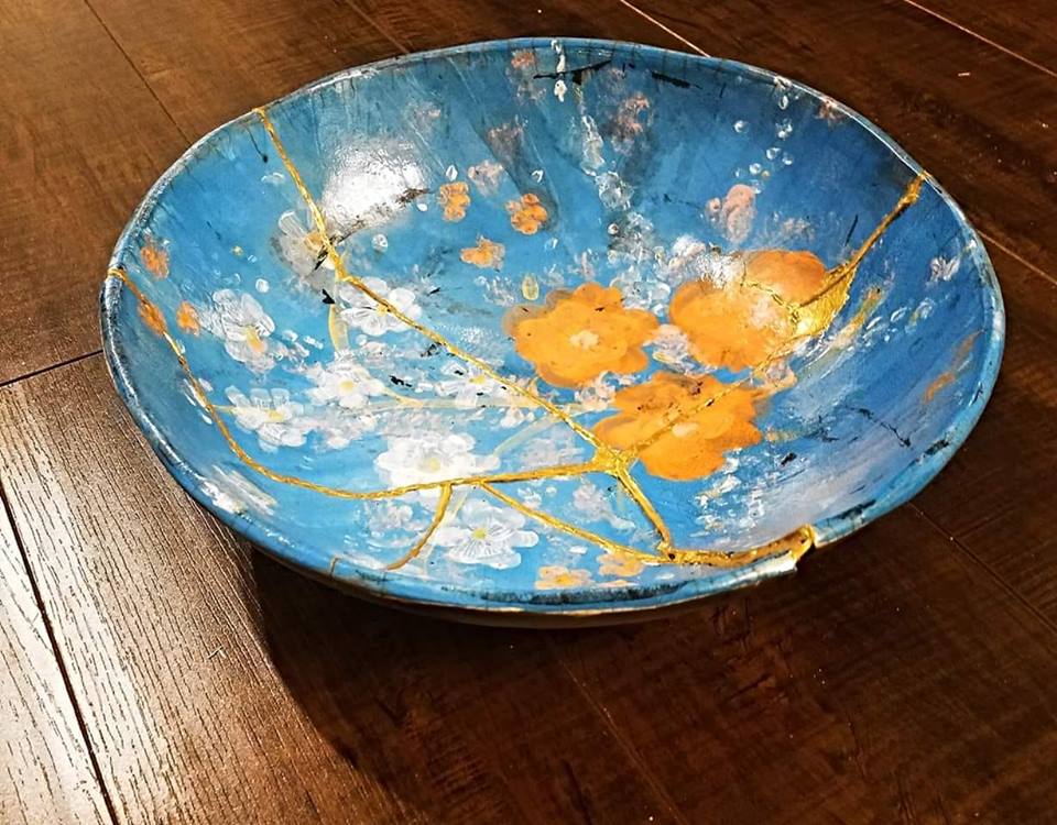 Decorative bowl with blue and gold design on a wooden surface. Hand Pinted Kintsugi Pottery Bowl