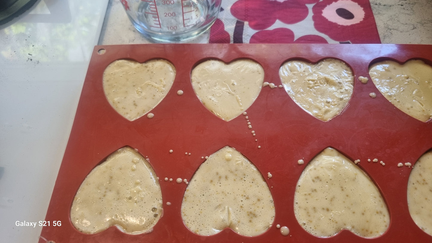 Heart-shaped cookie dough in a silicone mold on a floral-patterned surface.