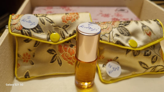 Small bottle of perfume with floral-patterned case on a light surface