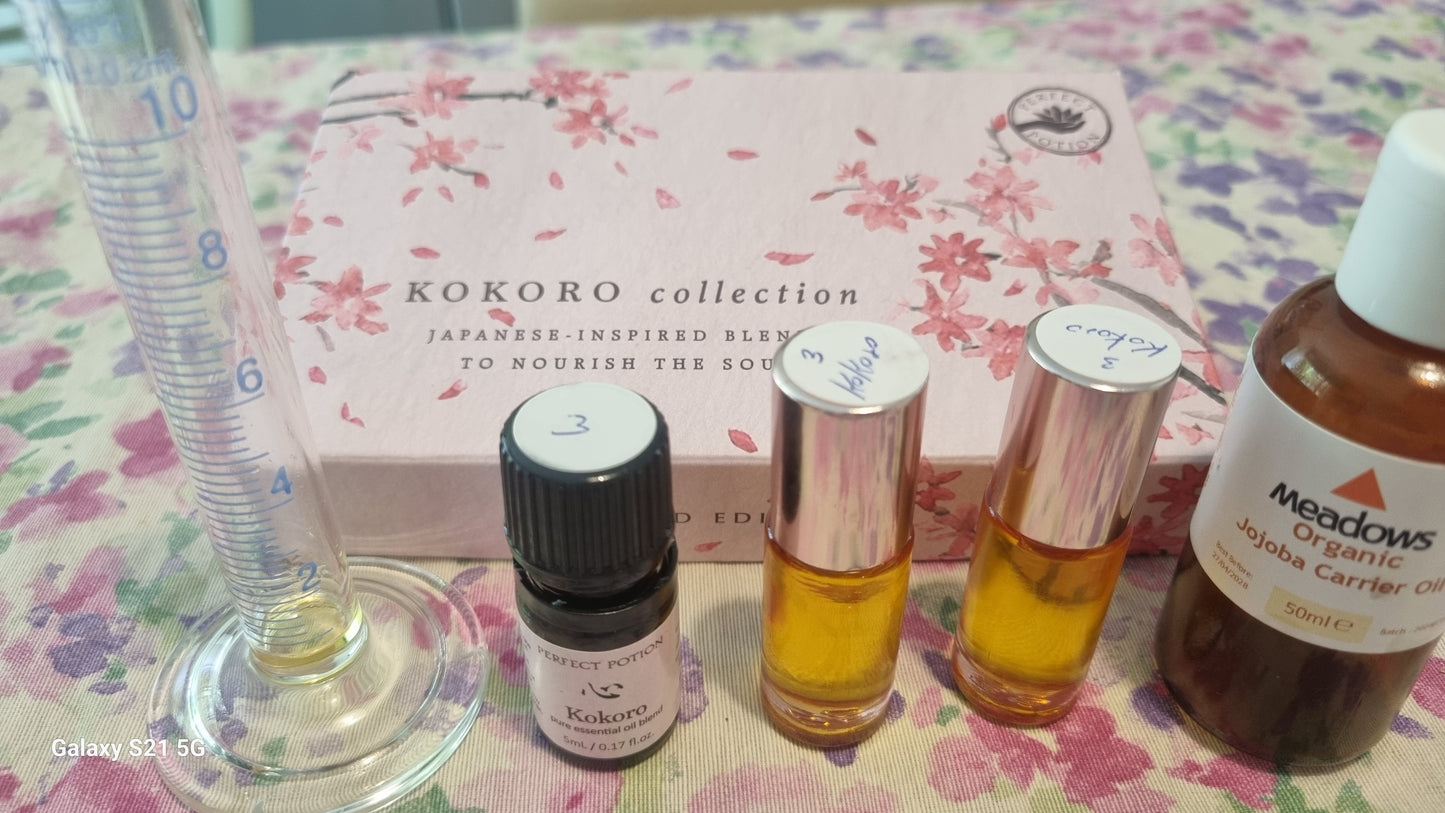 Set of essential oil bottles and a box labeled 'Kokoro collection' on a floral surface.