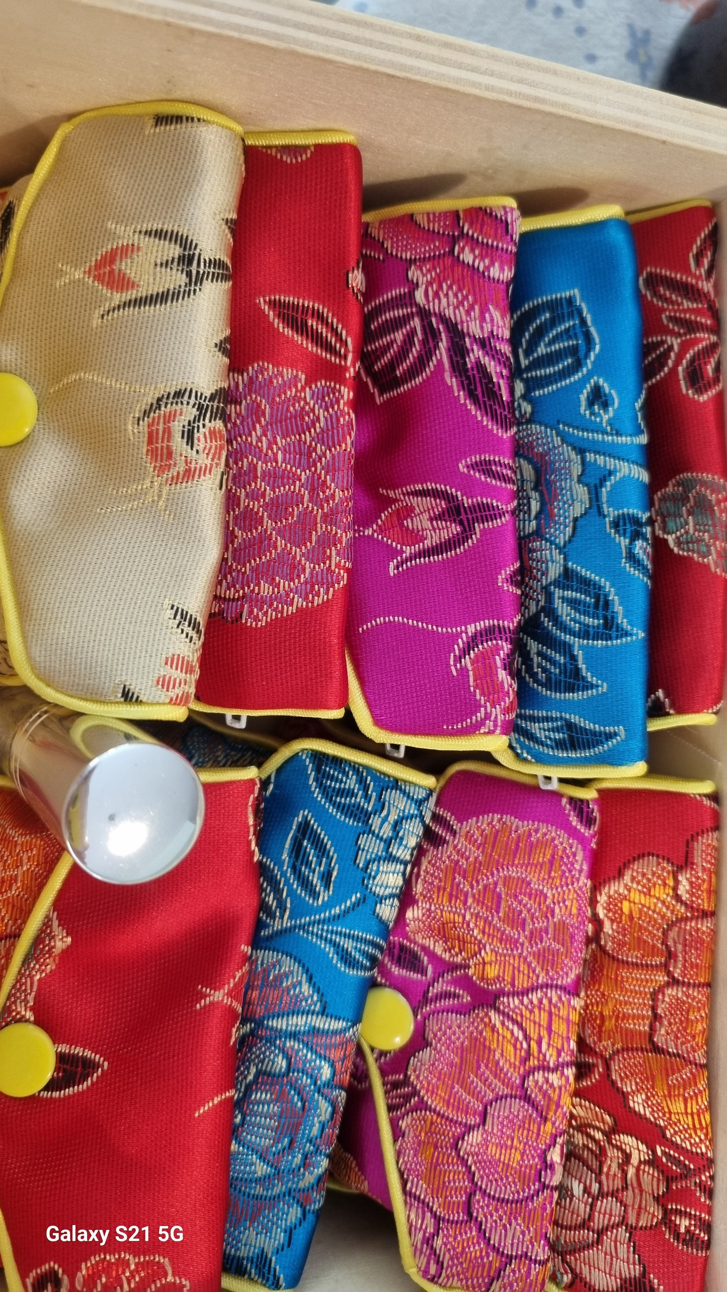Colorful fabric pouches with floral patterns arranged in a box.