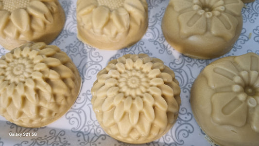 A selection of natural soaps with floral patterns, displayed on a textured background.