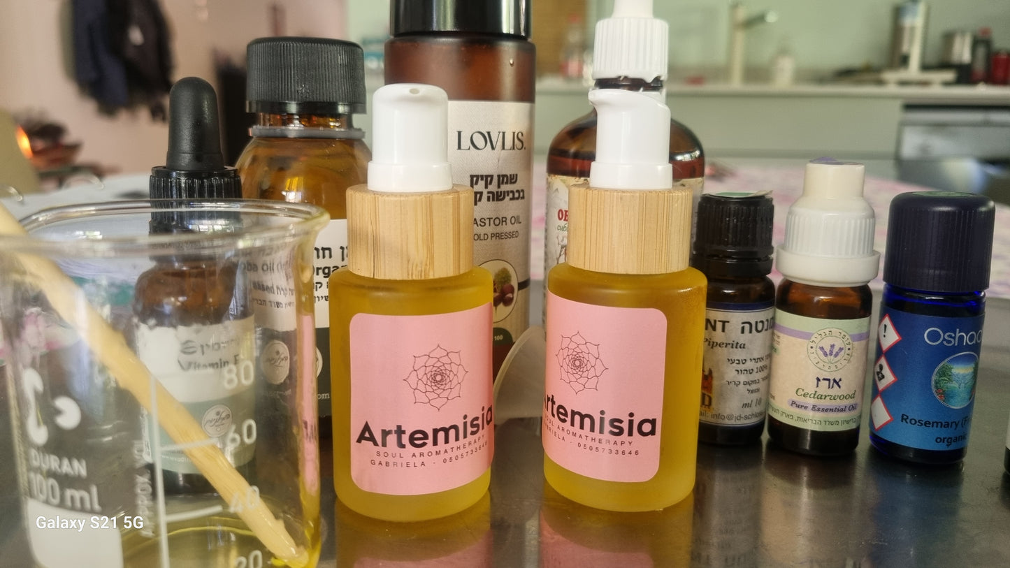 Two small glass bottles with dropper caps labeled 'Artemisia', containing a yellowish liquid, alongside a red rose. All placed on a table with a rose-themed tablecloth.