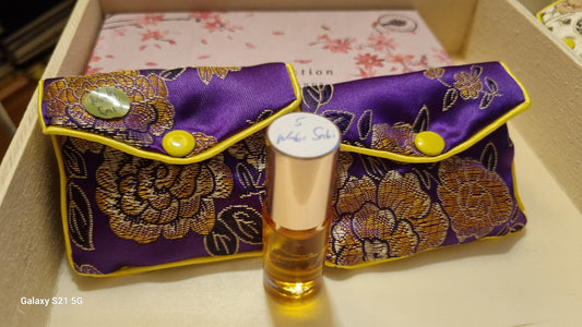 Perfume bottle with a decorative purple case on a light surface