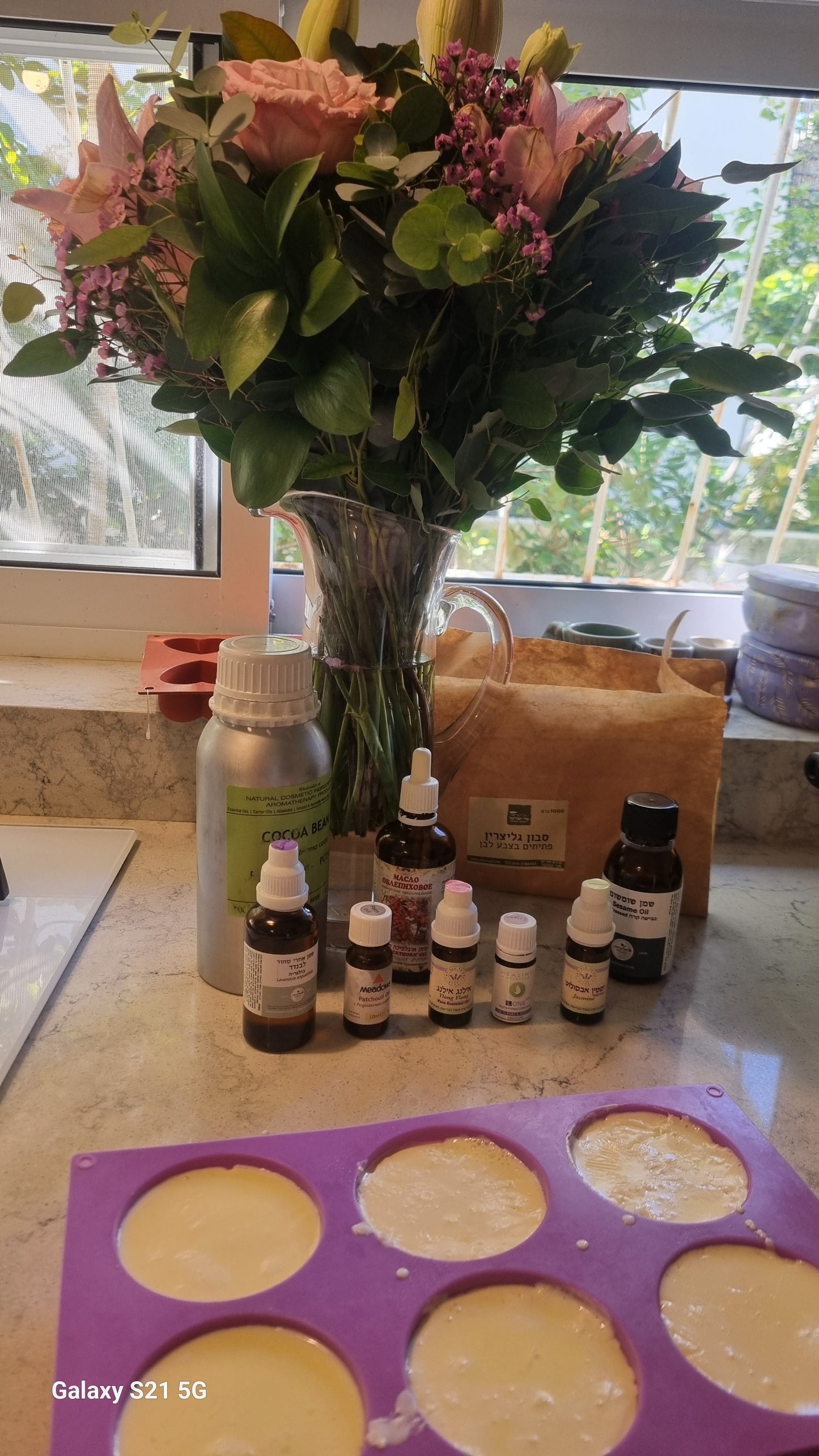 Bouquet of flowers on a table with bottles and a purple tray with circular objects.
