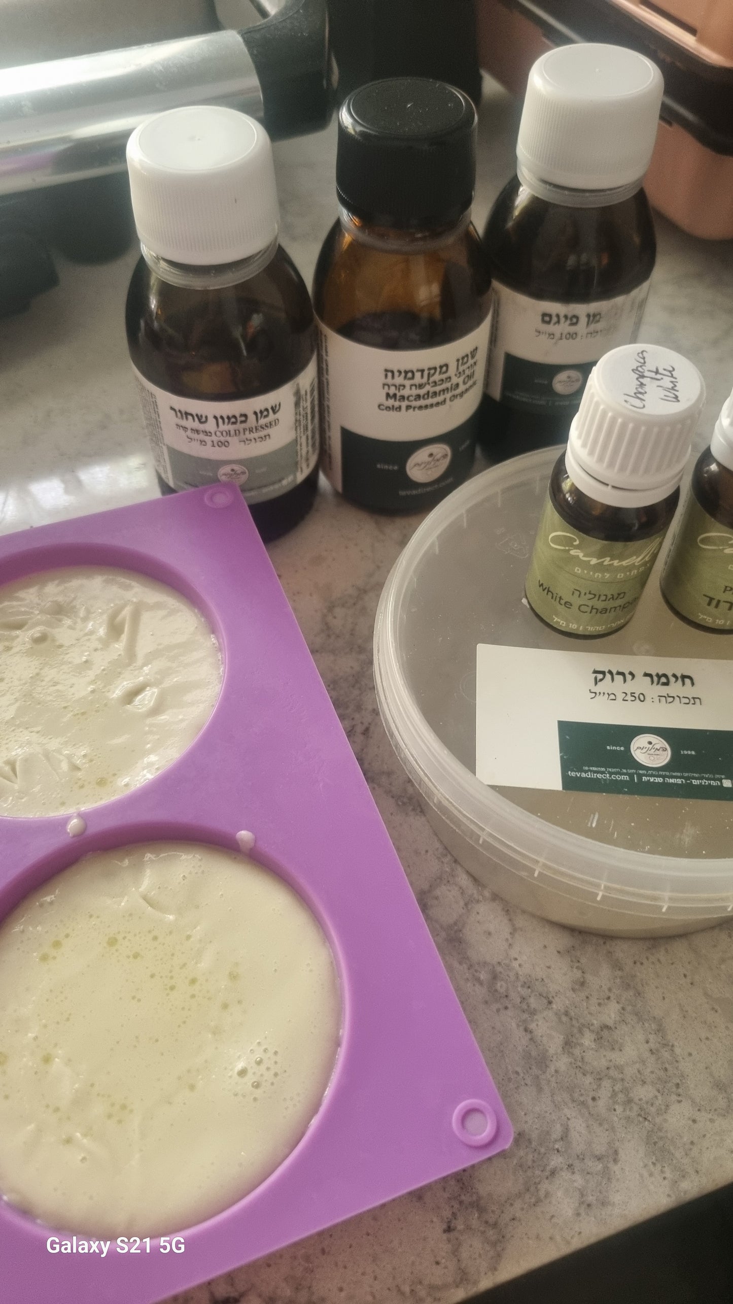 Bottles and containers on a surface with a purple silicone mold containing a white substance.