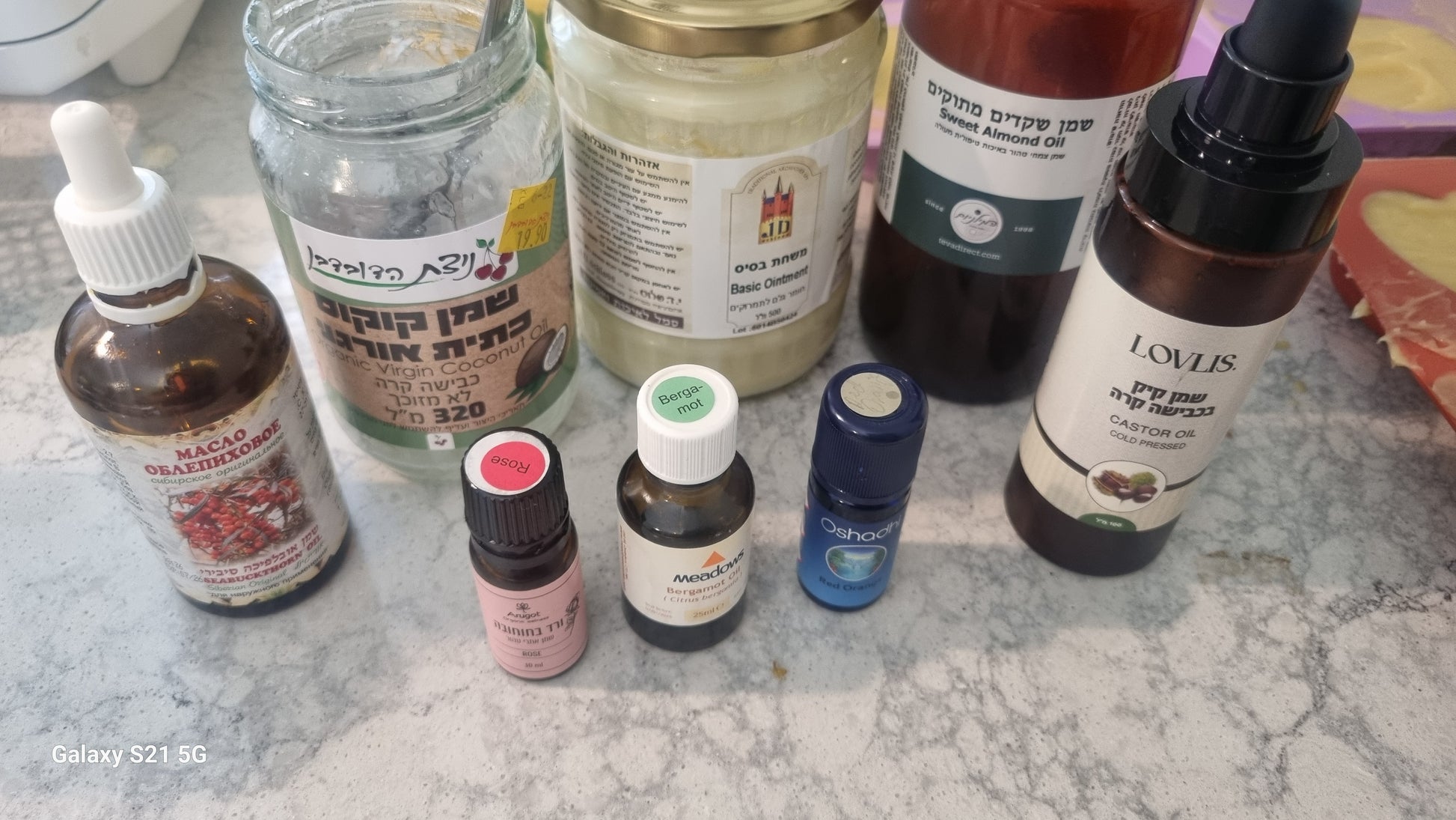 A collection of various bottles of essential oils and carrier oils. Rose, Bergamon and Red Orange Soap.